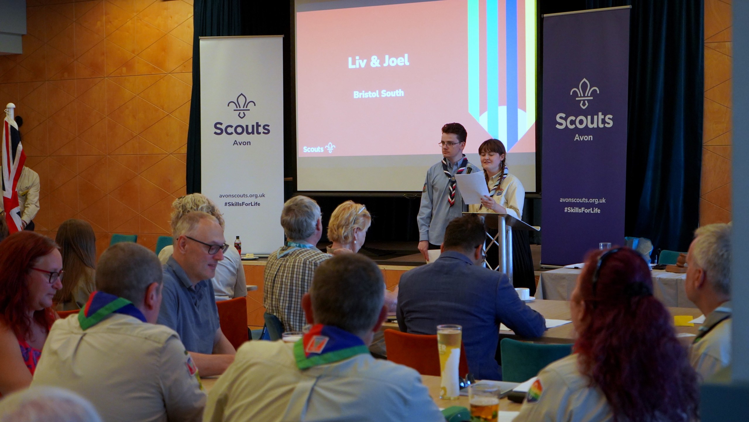 Two Explorer Scouts present at a lectern in front of a screen headed 'The highest award a young person can achieve'.